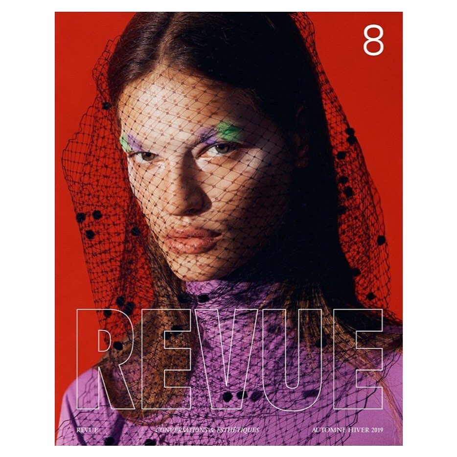 Fashion magazine cover featuring a woman with face net, colorful eye makeup, wearing a purple dress against a red background.