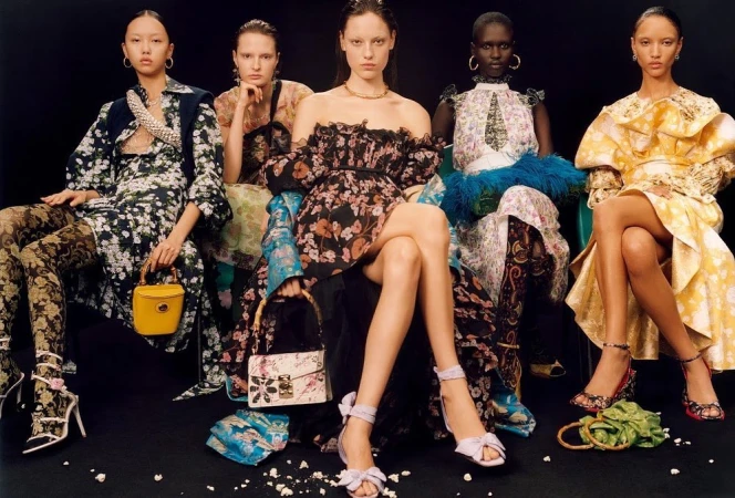 Five fashion models pose seated against a dark backdrop, showcasing floral print dresses, decorative tights, handbags, and stylish high heels.