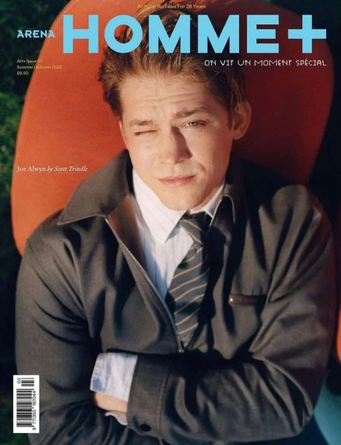 Magazine cover featuring a portrait of a young man with reddish hair, wearing a dark suit and tie, against an orange and green background.