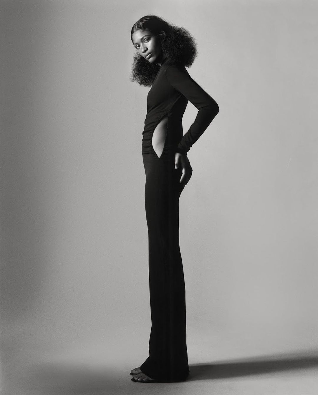 Black and white portrait of a model in a long black fitted dress with side cutout by Scott Trindle in Paris