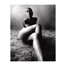 Monochrome portrait of a woman seated on a patterned rug indoors, photographed by Scott Trindle in Paris.