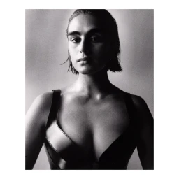 Monochrome portrait of a woman with dark hair wearing a sleeveless dark top against a plain light studio background.