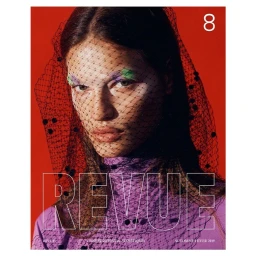 Model wearing purple turtleneck and black veil over face with green and purple eyeshadow