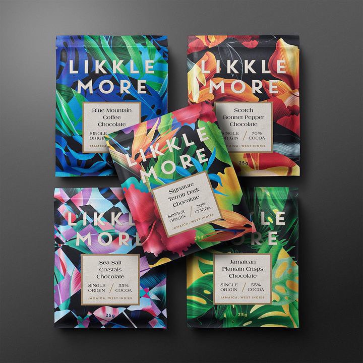 Collection of Likkle More chocolate bars with vibrant floral designs and tropical fruit flavors, beautifully arranged on a gray surface.