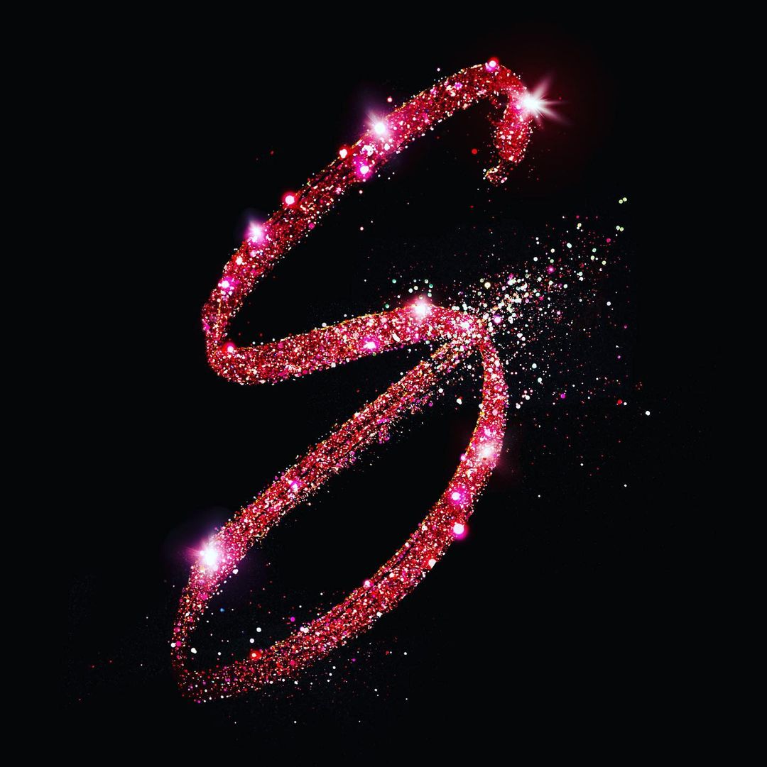 Sparkling red glitter forms the letter S against a black background, creating a visually striking and elegant design element.