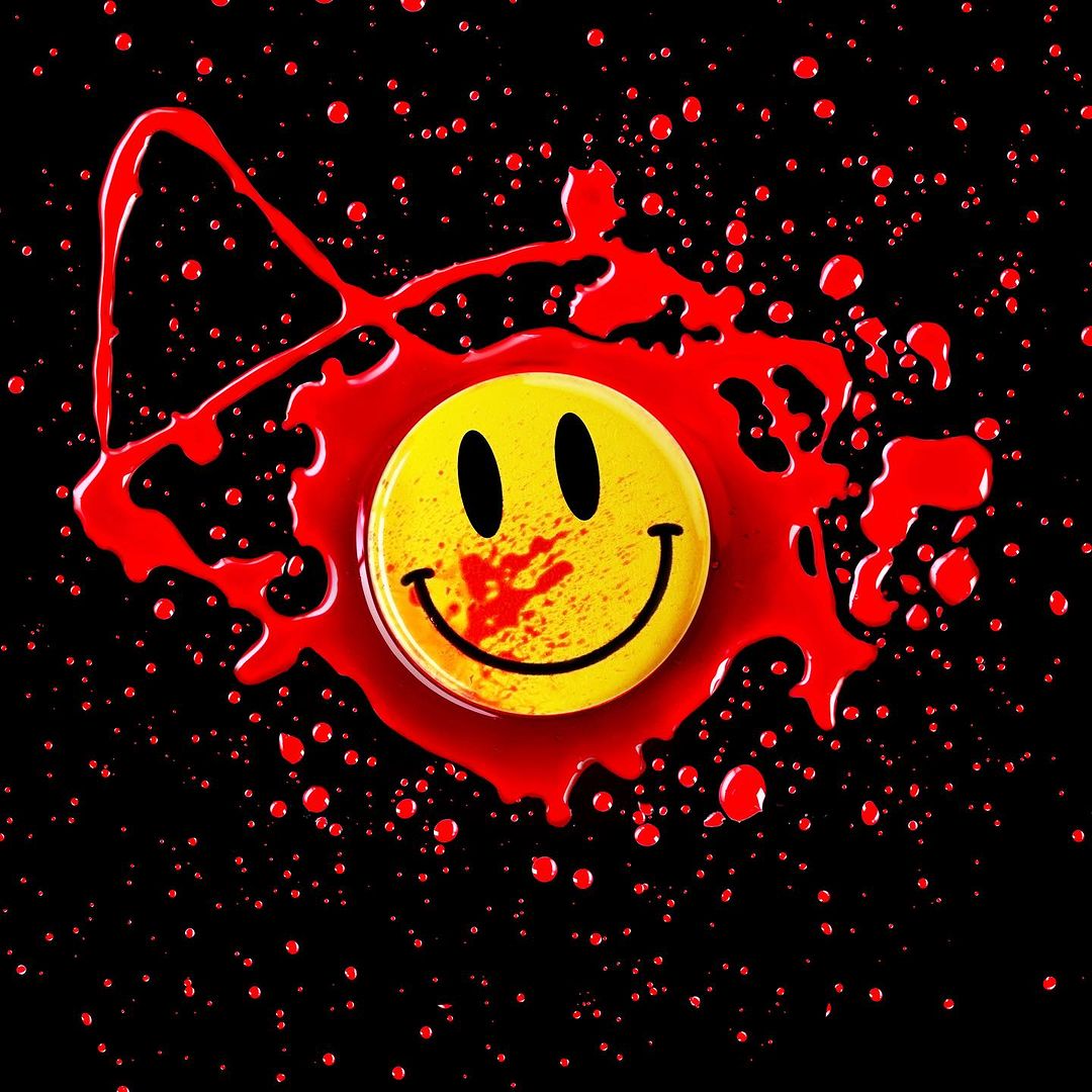 Smiley face button surrounded by bright red liquid splatters on a black background creating a visually striking and artistic contrast.