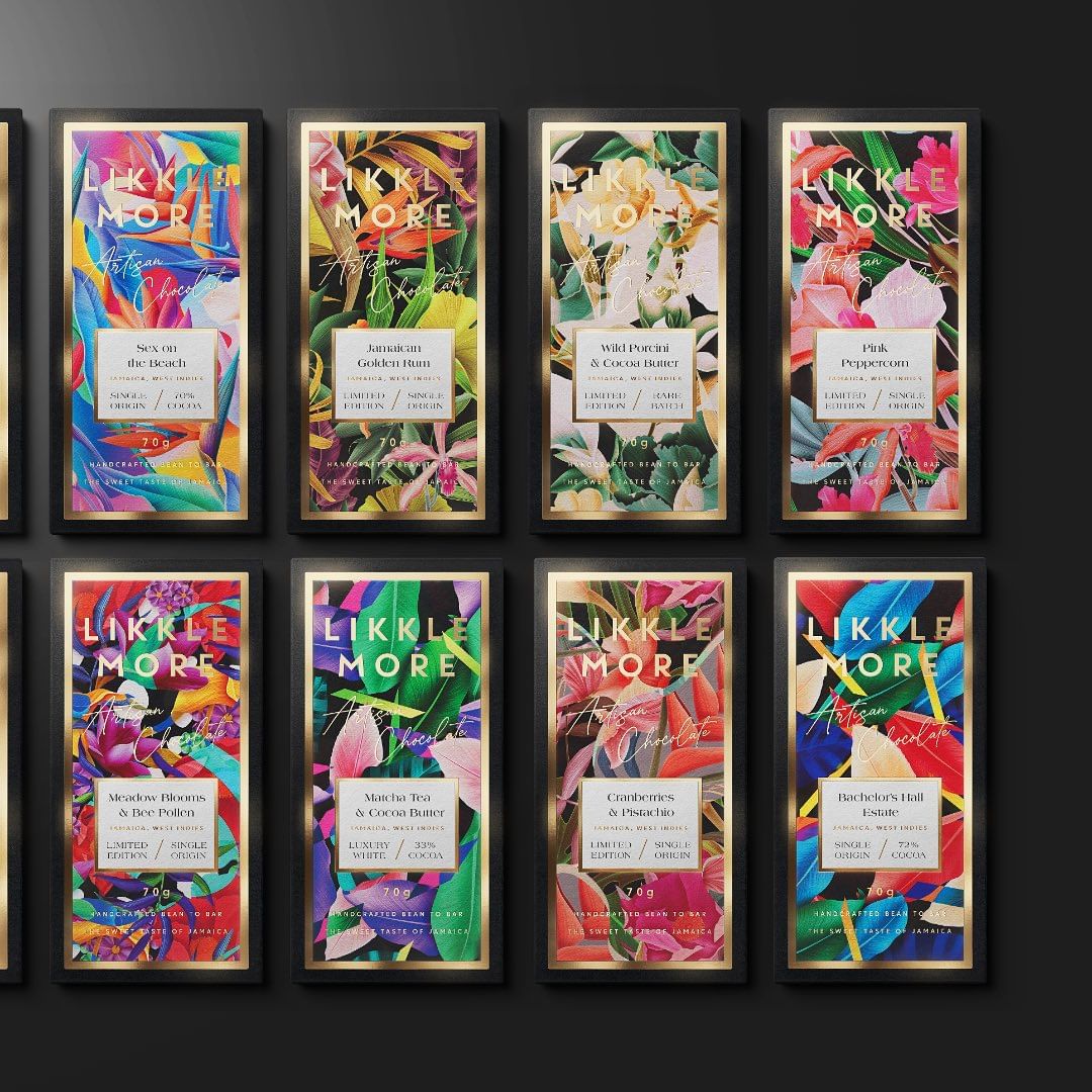 Overhead shot of Likkle More artisan chocolate bars in black frames, showcasing vibrant floral designs and flavor labels.