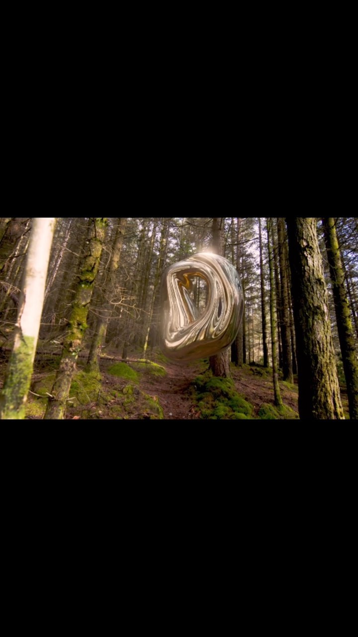 Abstract metallic, looping shape suspended in a sunlit forest with tall trees and soft mossy ground cover in a surreal scene.