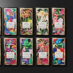 A flat lay of eight chocolate bar packaging designs featuring vibrant botanical tropical leaf prints with gold frames against a dark background.
