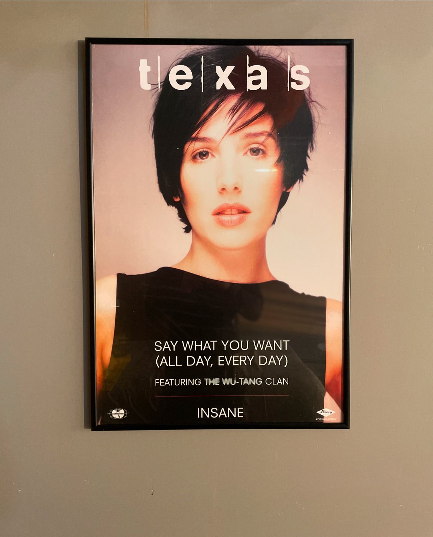 Framed "Texas" music poster featuring a woman, black tank top, and album title on a neutral wall, offering a vintage aesthetic.