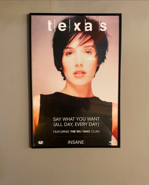 Framed "Texas" music poster featuring a woman, black tank top, and album title on a neutral wall, offering a vintage aesthetic.