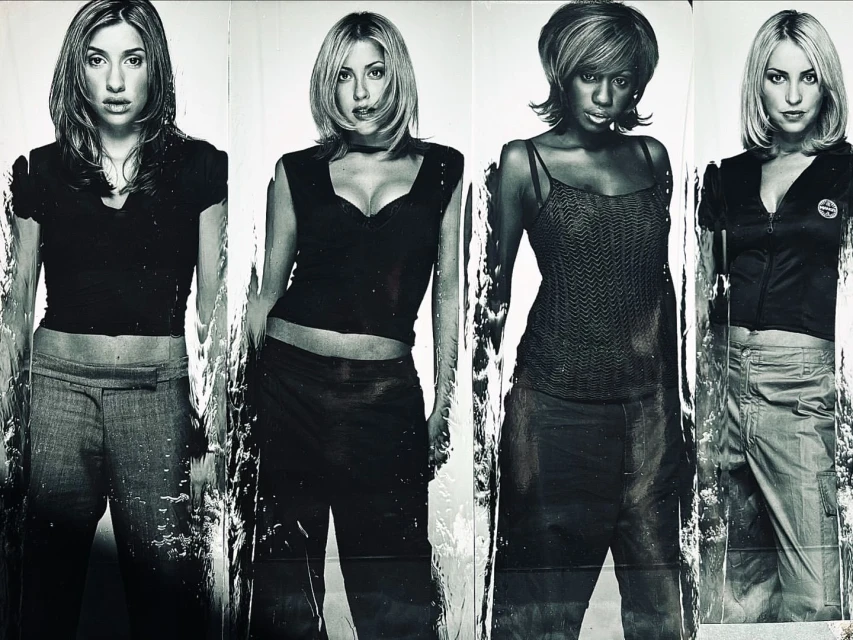 Black and white photo of four women posing, wearing casual outfits, showcasing fashion and style in a monochrome aesthetic.