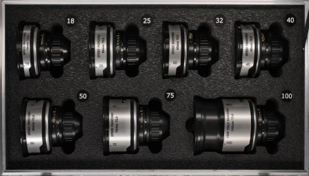 Overhead view of a hard camera case filled with seven professional cine lenses arranged in custom foam cutouts.