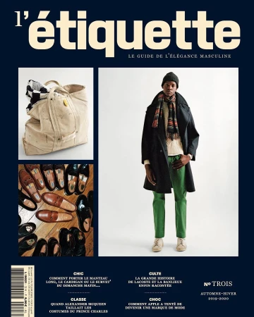 A magazine cover with a man in a dark coat and green pants, a travel bag, and shoes, set against a navy blue background.
