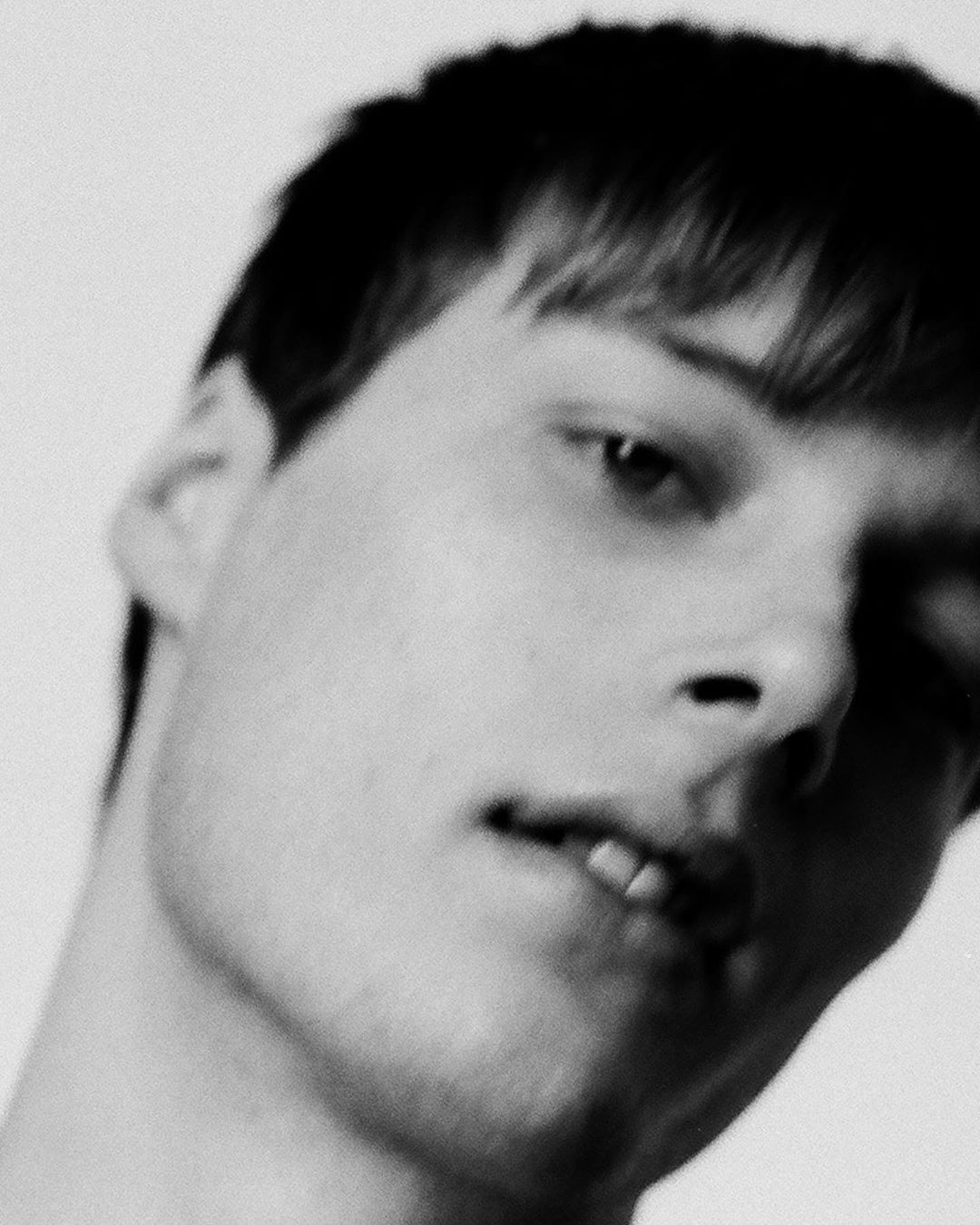 Monochromatic close-up portrait of a fair-skinned adult male with short dark hair, featuring a neutral expression and bright, even lighting.
