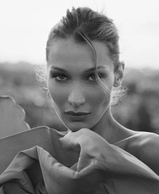 Striking portrait of a woman with neutral expression in front of a blurred background, black and white photography.