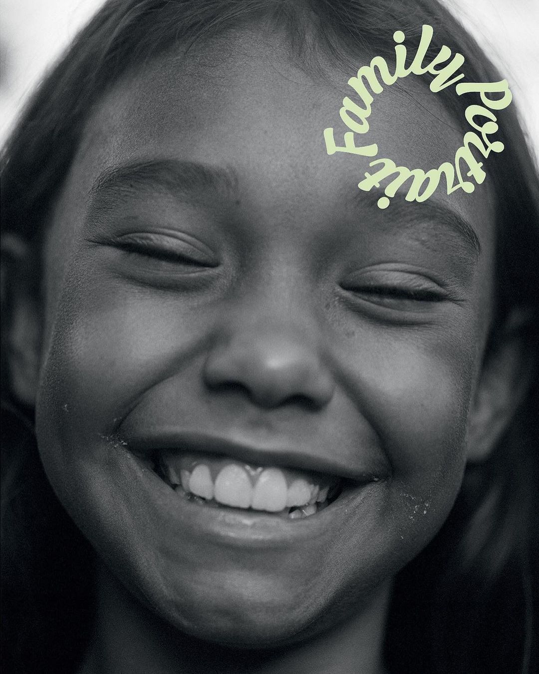 A close-up, black and white portrait of a smiling child with closed eyes, featuring light green text overlay that reads 'Family Portrait'.