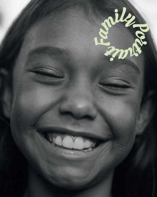 A close-up, black and white portrait of a smiling child with closed eyes, featuring light green text overlay that reads 'Family Portrait'.