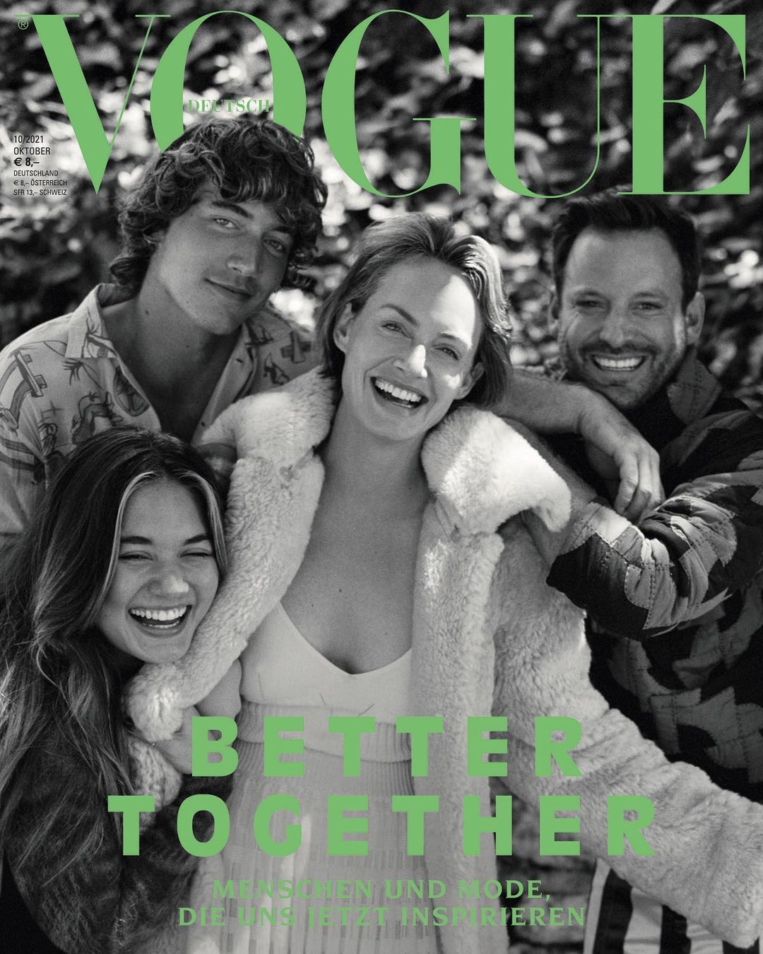 Vogue cover featuring four smiling people huddled together outdoors; fashion magazine cover showcases a group of diverse individuals.