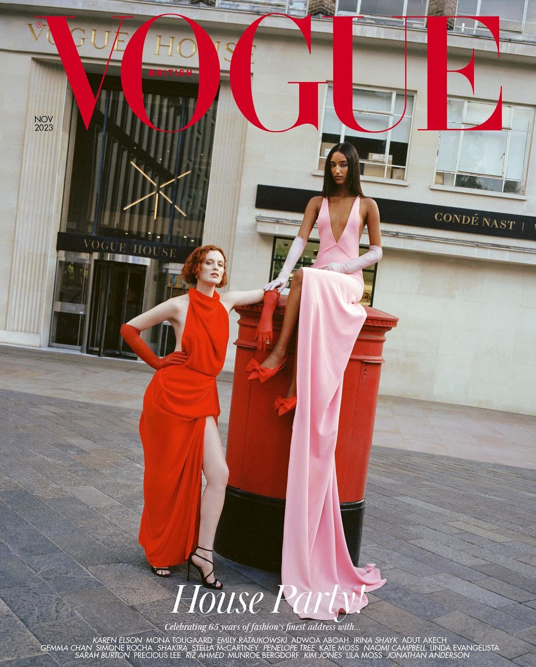 Vogue magazine cover featuring two fashion models in elegant gowns posing on a street with building and red postal box background.