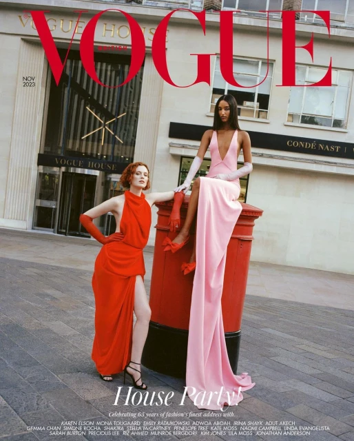 Vogue magazine cover featuring two fashion models in elegant gowns posing on a street with building and red postal box background.