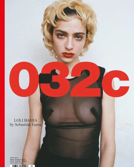 Close-up portrait of a young woman with blonde curly hair, red lipstick, and a sheer top posing in front of a white background and red text.