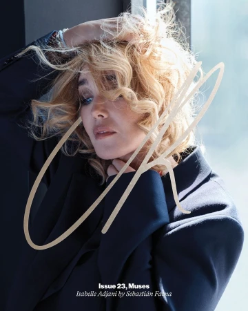 Blonde woman with curly hair wearing a dark blazer holding her hair in a portrait by Sebastian Faena