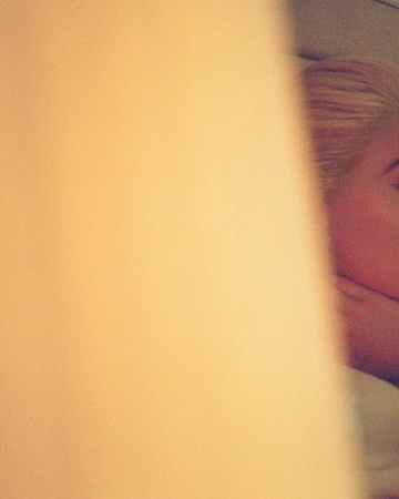Close-up portrait of a blonde woman partially obscured by a warm, out-of-focus foreground element by Sebastian Faena.