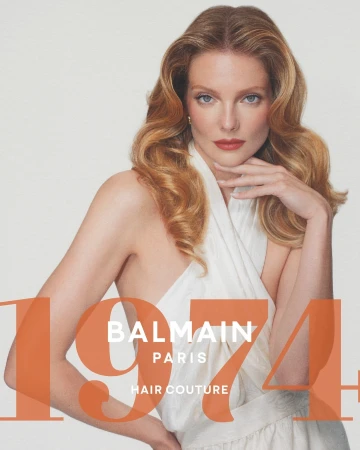 Close-up portrait of a woman with blonde wavy hair wearing a white halter top against a light background with orange typography.