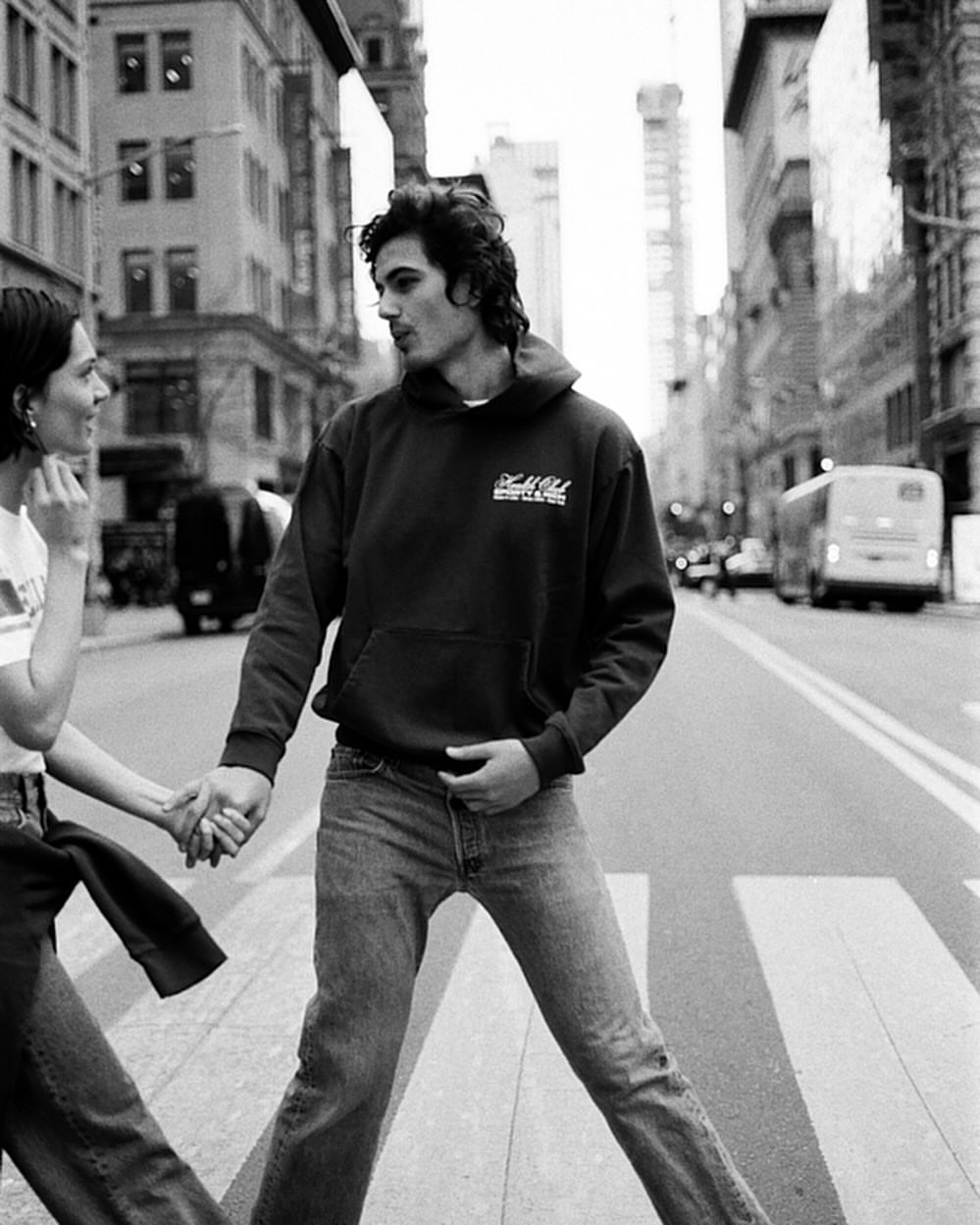 Man and woman holding hands walking across a New York street in a black and white photograph by Sebastian Sabal-bruce.