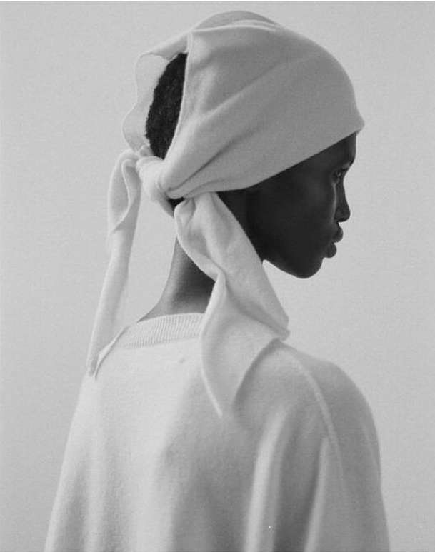 Monochrome portrait of a Black woman in a white headscarf and sweater against a pale background by Sebastian Sabal-bruce.