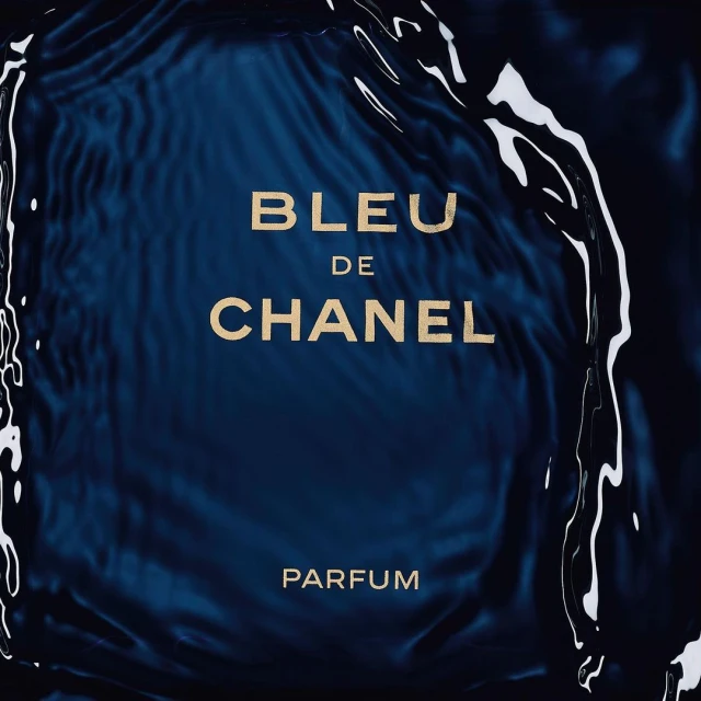 Bleu de Chanel Parfum displayed with water droplets on a dark blue background, creating an evocative and visually appealing image.