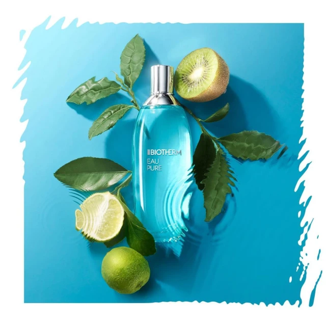 Turquoise bottle of Biotherm Eau Pure surrounded by limes, kiwi, and green leaves against a matching turquoise background.