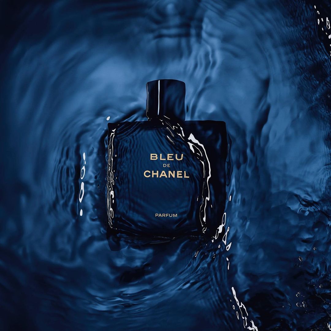 Chanel Bleu de Chanel Parfum bottle centered in a blue water ripple background, product photography, studio lighting, dark blue color grade.