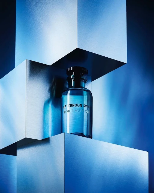 Louis Vuitton Afternoon Swim perfume bottle on metallic blue stacked cube platforms, creating a modern and sleek aesthetic.