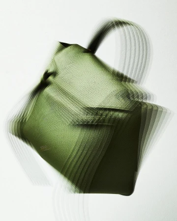 Olive green leather handbag with blurred motion effect on white background in a studio setting for a fashion product shot.