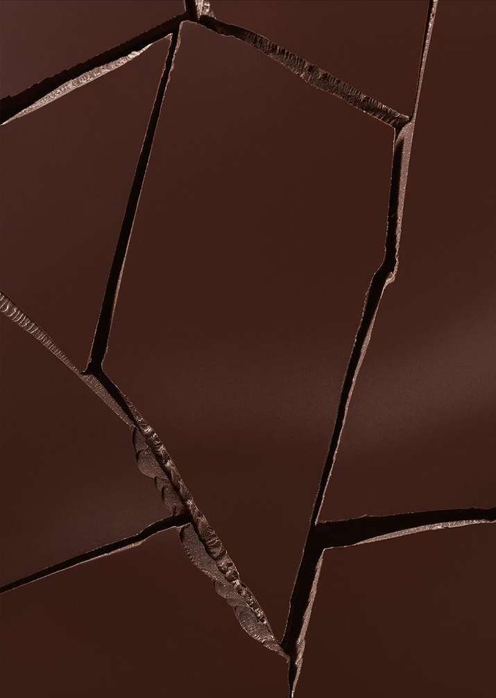Close-up overhead shot of broken dark chocolate pieces creating irregular patterns and texture, ideal for food and dessert themes.