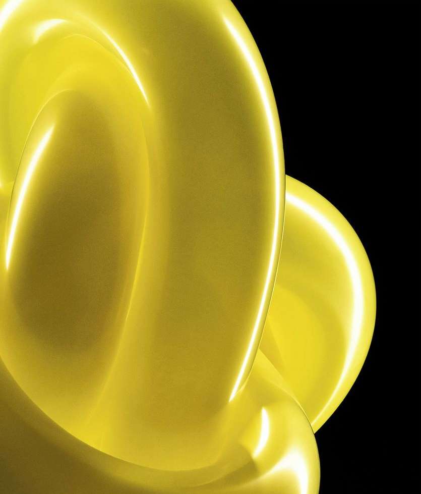 Abstract yellow looping object with glossy surface against a black background in a studio setting, featuring an artful presentation.