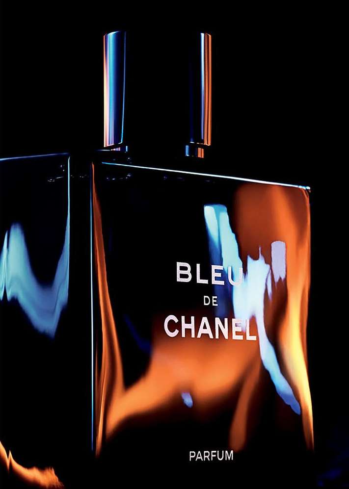 Bleu de Chanel Parfum: A sleek, dark-toned still life captures a reflective perfume bottle with its cap, set against a dark background.