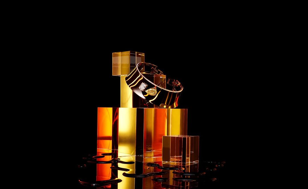 Elegant black and gold gemstone-studded bracelet on reflective blocks against a black background, showcasing luxury jewelry.