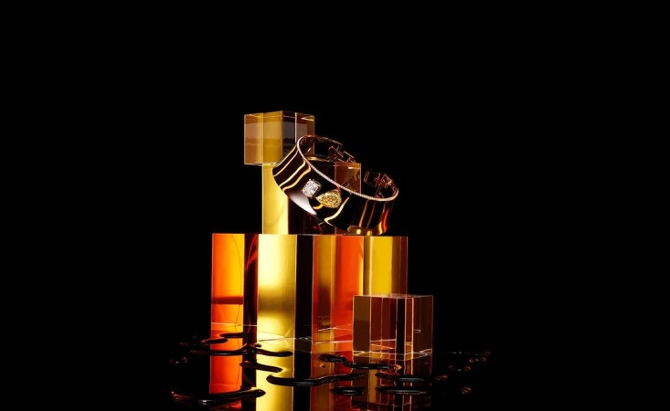 Elegant black and gold gemstone-studded bracelet on reflective blocks against a black background, showcasing luxury jewelry.