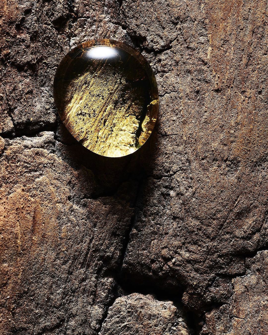Textured stone surface with a single, clear water droplet reflecting the surface beneath it, creating an abstract and natural composition.