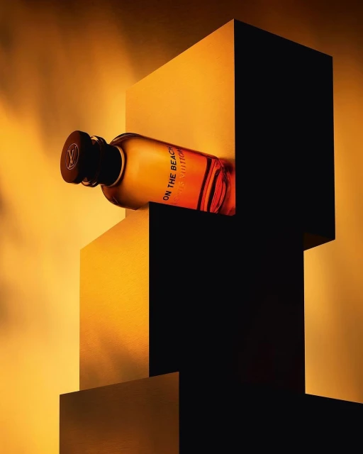 Product shot of a Louis Vuitton On the Beach fragrance bottle against geometric shapes and warm lighting, creating a modern, luxury aesthetic.