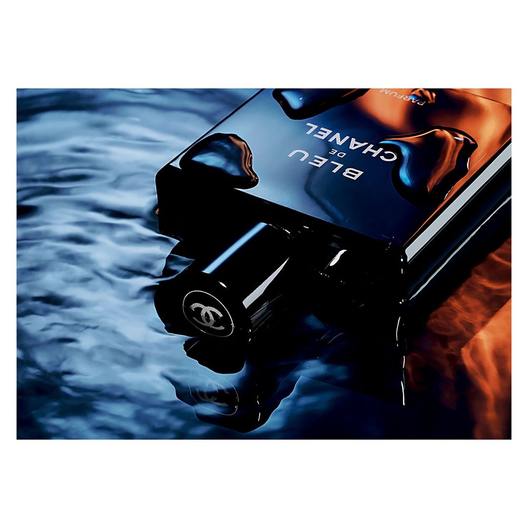 Close-up of a Bleu de Chanel bottle with water droplets, capturing its sleek design and highlighting the product's luxury appeal.