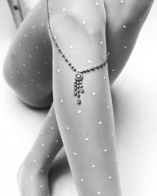 Close-up studio shot of a woman's legs adorned with a delicate jeweled anklet over polka dot tights, creating a sophisticated visual.