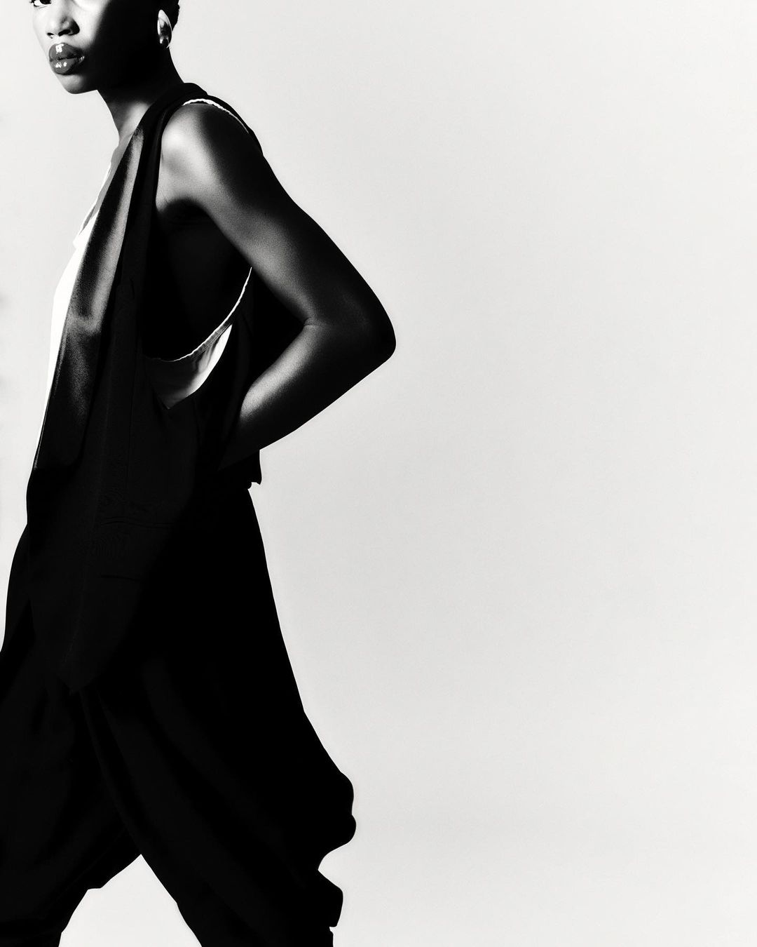 Black and white portrait of a model with short hair wearing a dark sleeveless top against a white background by Sebastien Giraud