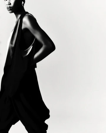 Black and white portrait of a model with short hair wearing a dark sleeveless top against a white background by Sebastien Giraud