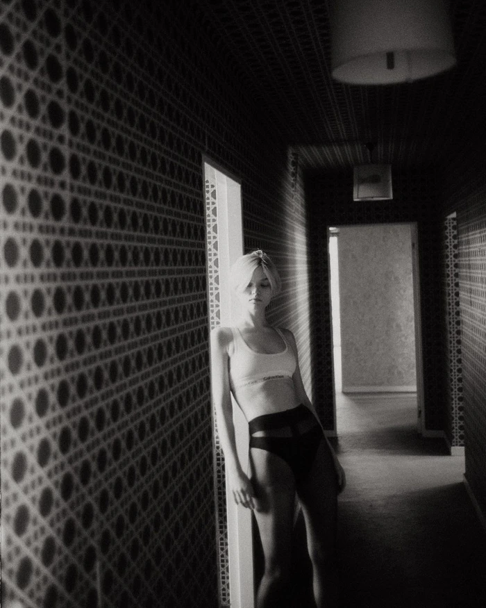 Black and white portrait of a woman leaning against a patterned hallway doorframe