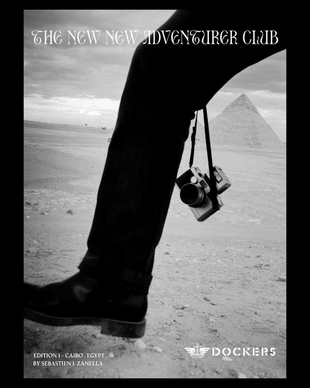 Black and white landscape photograph featuring a leg, camera, pyramid, and desert under an overcast sky. Dockers ad, Egypt.