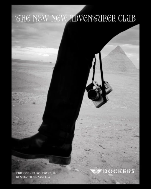 Black and white landscape photograph featuring a leg, camera, pyramid, and desert under an overcast sky. Dockers ad, Egypt.